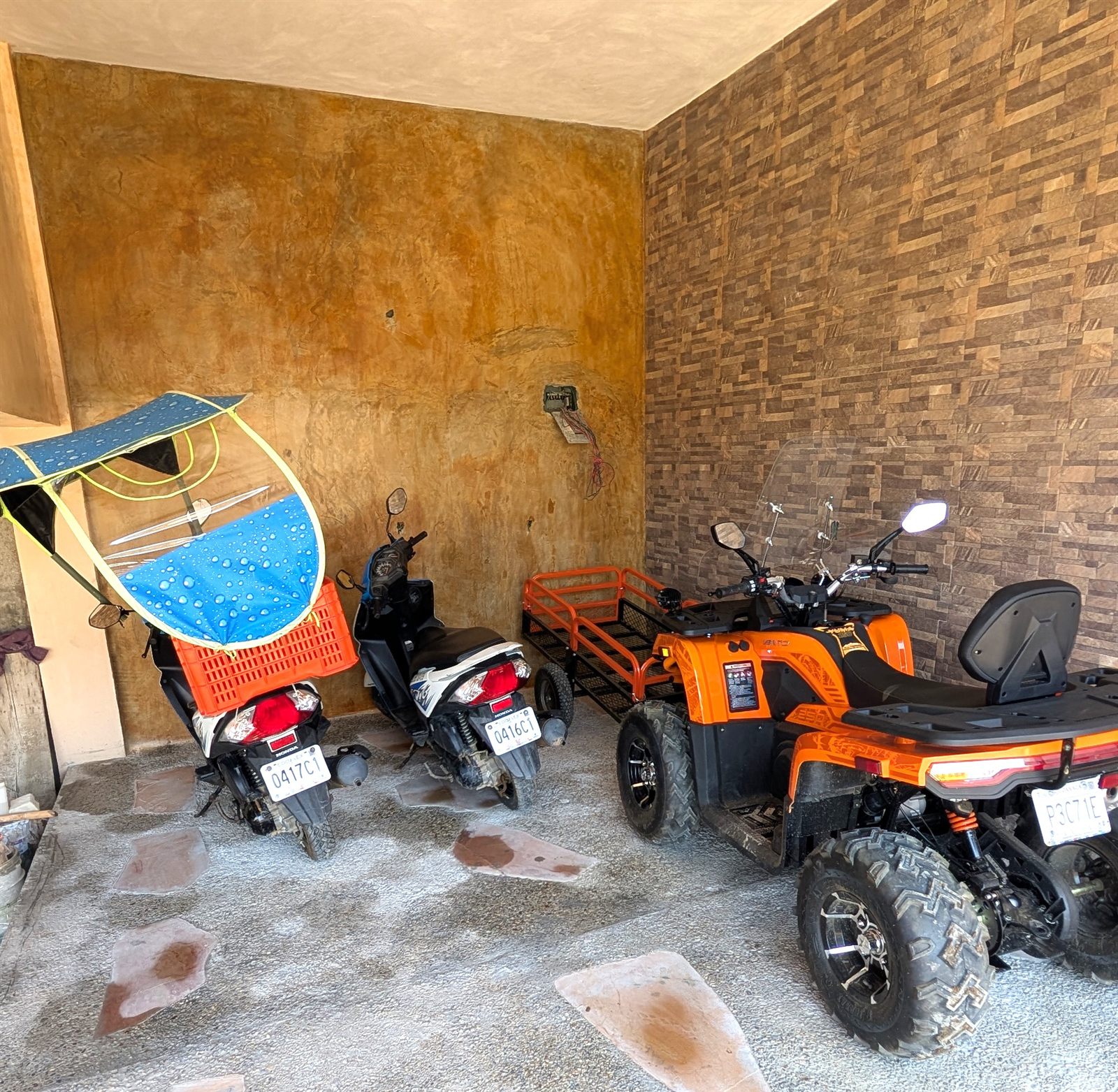 The garage, with scooters and a quad bike parked against a stone wall.