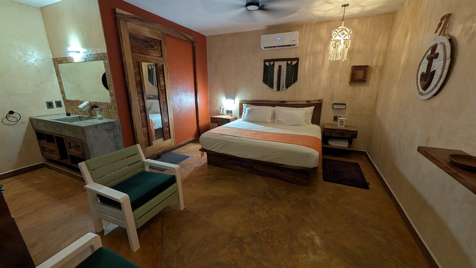 A room with a wooden bed, a concrete basin and an anchor on the wall.