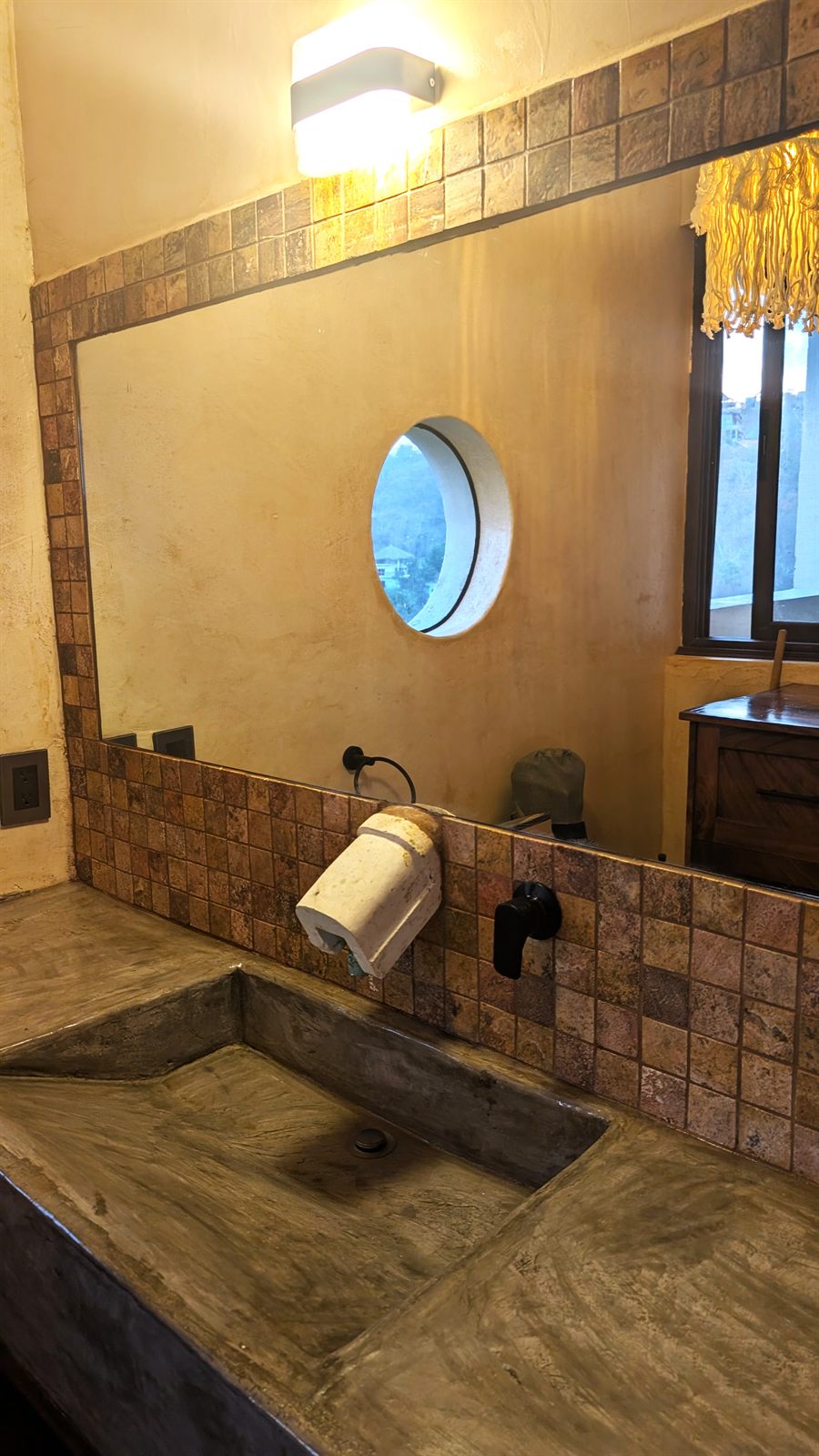 The bathroom: a poured concrete basin, stone tile and a round window.
