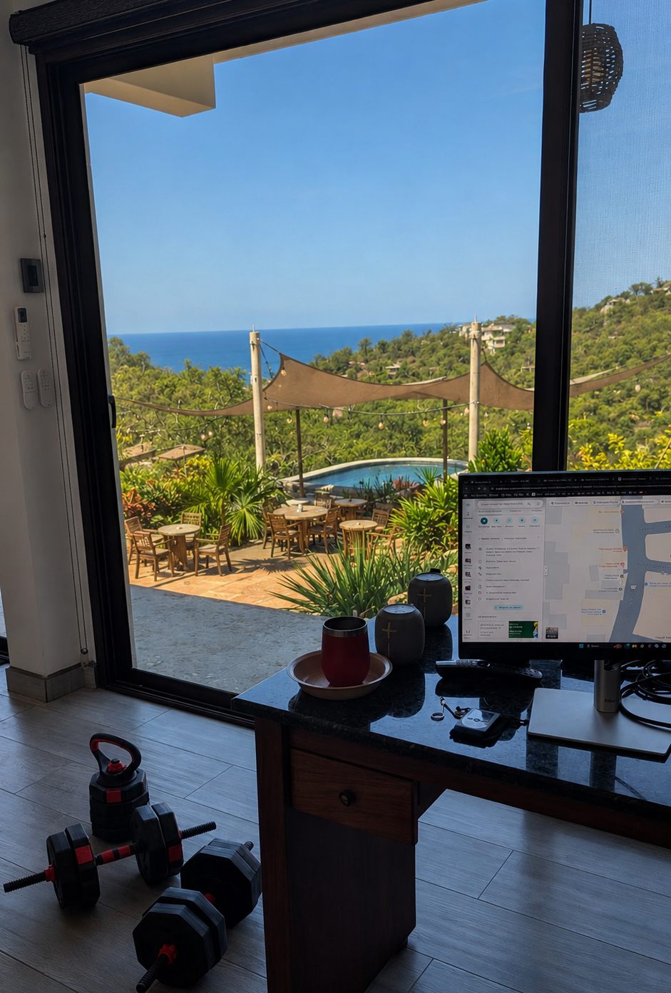 A desk facing an open door, the pool and the Pacific beyond.
